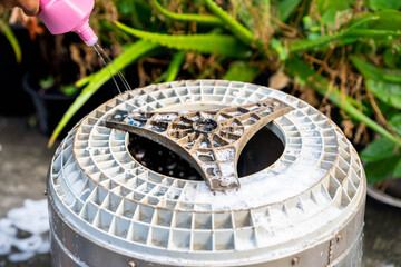 Wash the inside of the washing machine. The human hand is squeezing the bottle cleaning solution to erode the dirt that adheres to the base of the automatic washing machine.