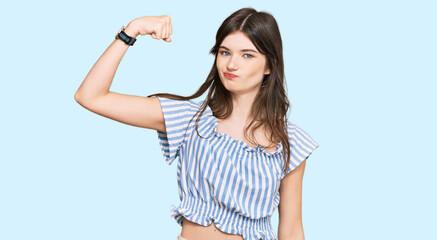 Young beautiful caucasian girl wearing casual clothes strong person showing arm muscle, confident and proud of power
