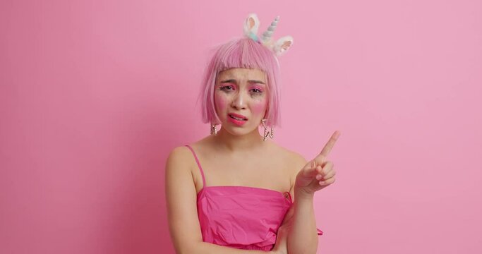 Upset Asian female model shakes index finger says no I deny this looks self confident has dissatisfied face expression wears festive dress isolated over pink background. Dont bother me please