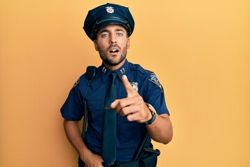 Handsome hispanic man wearing police uniform pointing displeased and frustrated to the camera,...