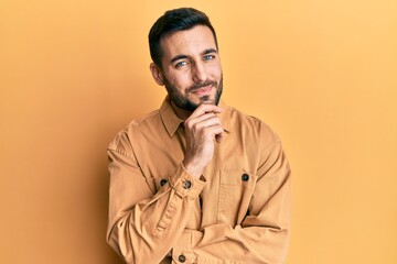 Young hispanic man wearing casual clothes smiling looking confident at the camera with crossed arms and hand on chin. thinking positive.