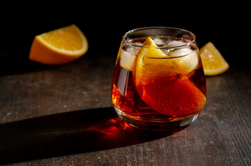 Negroni cocktail with prange slice with shadow on dark
