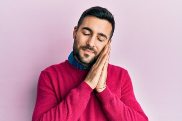 Young hispanic man wearing casual clothes sleeping tired dreaming and posing with hands together while smiling with closed eyes.