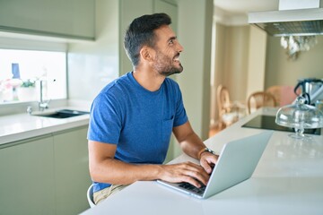 Fototapeta premium Young handsome man smiling happy working using laptop at home