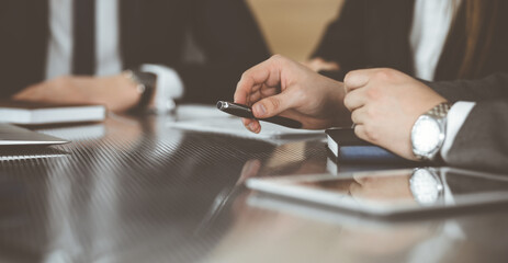 Unknown businessmen and woman sitting, working and discussing questions at meeting in modern office, close-up