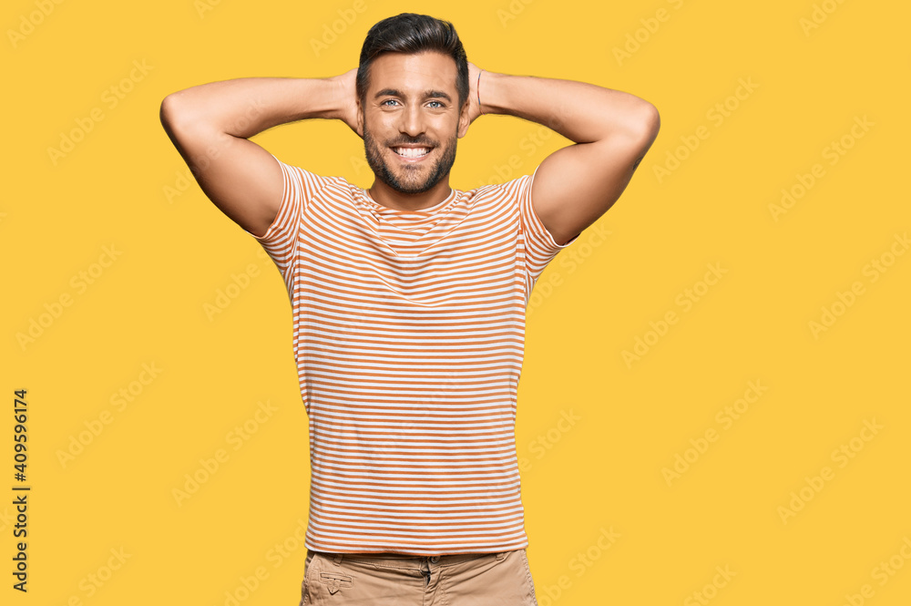 Wall mural Handsome hispanic man wearing casual clothes relaxing and stretching, arms and hands behind head and neck smiling happy