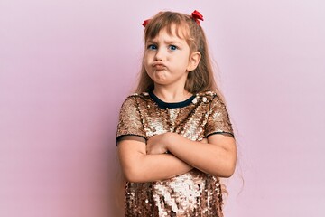 Little caucasian girl kid wearing festive sequins dress skeptic and nervous, disapproving expression on face with crossed arms. negative person.
