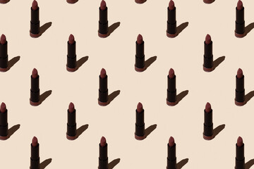Seamless lipstick pattern on a beige background. Female cosmetic product for makeup