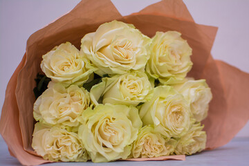 A bouquet of light roses in wrapping paper.