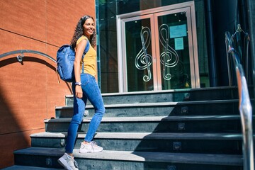 Young african american student girl smiling happy going up stairs of music academy.