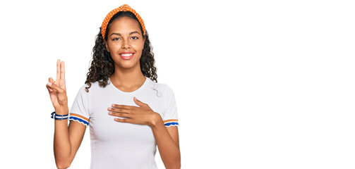 Young african american girl wearing casual clothes smiling swearing with hand on chest and fingers...