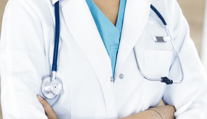 Unknown female doctor standing with arms crossed in clinic, close-up. Medicine concept