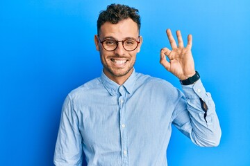 Young hispanic man wearing casual clothes and glasses smiling positive doing ok sign with hand and fingers. successful expression.