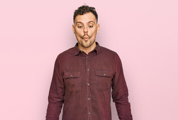 Young hispanic man wearing casual clothes making fish face with lips, crazy and comical gesture. funny expression.