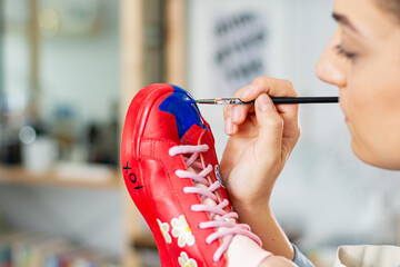 Close-up of woman customizing and repainting sneakers with new designs