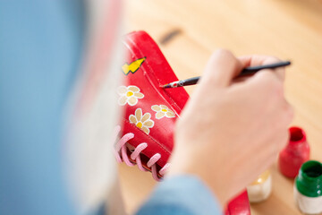 Close-up of woman repainting and customizing old shoes, eco-fashion concept