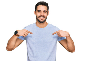 Young hispanic man wearing casual clothes looking confident with smile on face, pointing oneself...