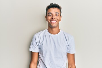 Obraz premium Young handsome african american man wearing casual white tshirt with a happy and cool smile on face. lucky person.