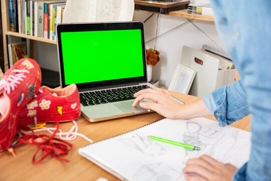 Fashion designer using laptop while working in workshop, green screen - Powered by Adobe