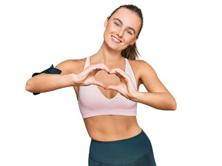 Fototapeta premium Beautiful young blonde woman wearing sportswear and arm band smiling in love showing heart symbol and shape with hands. romantic concept.