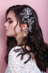 Fototapeta premium Portrait of beautiful woman wedding model with jewelry on hair looking away on pink background