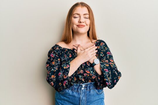 Young beautiful redhead woman wearing casual floral clothes smiling with hands on chest, eyes closed with grateful gesture on face. health concept.