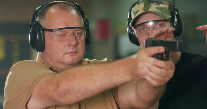 A man learns how to shoot a gun at the shooting range.