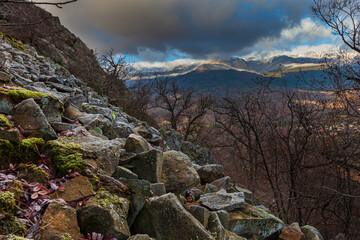 rocky landscape in the mountain with a few trees and vivid clouds