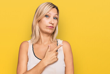 Middle age caucasian woman wearing casual clothes pointing with hand finger to the side showing advertisement, serious and calm face