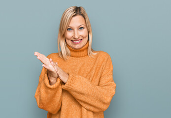 Middle age caucasian woman wearing casual winter sweater clapping and applauding happy and joyful, smiling proud hands together
