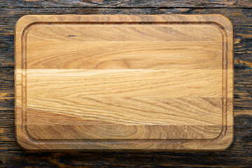 Cutting wooden board of rectangular shape on a wooden background.  Space for text.