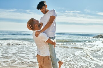 Romantic gay couple smiling happy hugging at the beach.