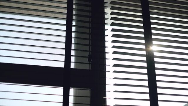 The sunlight shines through the black wooden blinds in the bedroom 4k
