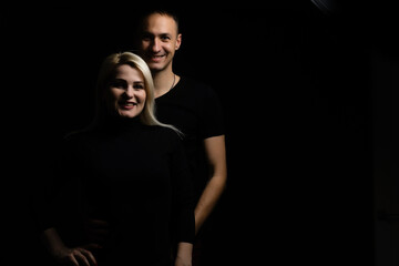 Young couple in love hug each other on the black background