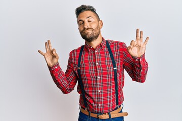 Fototapeta premium Handsome man with beard wearing hipster elegant look relax and smiling with eyes closed doing meditation gesture with fingers. yoga concept.