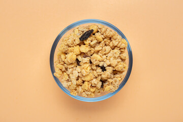 Cereal. Breakfast with muesli and raisins in a glass bowl on a cream background. Space for text. Top view.