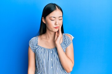 Young chinese woman wearing casual striped t-shirt touching mouth with hand with painful expression because of toothache or dental illness on teeth. dentist