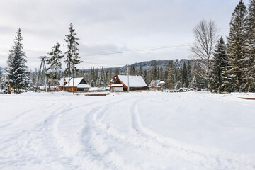 ZAKOPANE, POLAND - JANUARY 28, 2021: A settlement of small wooden houses near the forest, in the mountains. Winter landscape