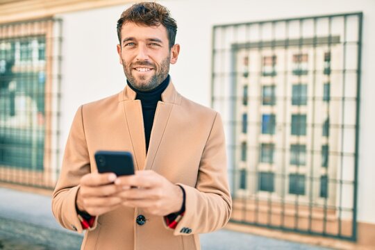 Handsome business man wearing elegant jacket using smartphone smiling happy outdoors