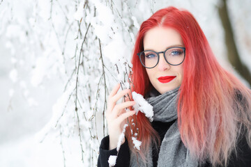 Smiling attractive red hair girl in glasses posing in wintry nature.