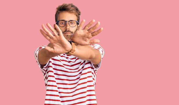 Handsome blond man with beard wearing casual clothes and glasses rejection expression crossing arms and palms doing negative sign, angry face