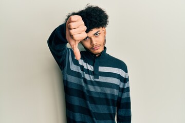 Young african american man with afro hair wearing casual clothes looking unhappy and angry showing rejection and negative with thumbs down gesture. bad expression.