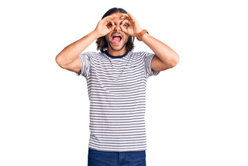 Fototapeta premium Young handsome man wearing casual clothes doing ok gesture like binoculars sticking tongue out, eyes looking through fingers. crazy expression.