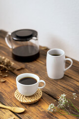 Obraz na płótnie Canvas Zwei weiße Tassen mit Kaffee und eine Glaskanne auf einem rustikalen Holz Tisch. Retro, Frühstück, Zuhause.