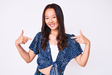 Young beautiful chinese girl wearing casual clothes looking confident with smile on face, pointing...