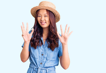 Obraz na płótnie Canvas Young beautiful chinese girl wearing summer hat showing and pointing up with fingers number nine while smiling confident and happy.