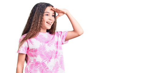 Cute hispanic child girl wearing casual clothes very happy and smiling looking far away with hand over head. searching concept.