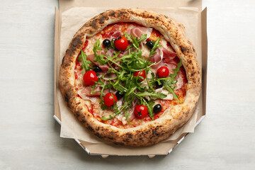 Tasty pizza with meat and arugula in cardboard box on white table, top view