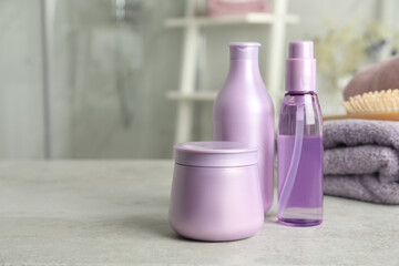 Set of hair care cosmetic products on light grey stone table in bathroom. Space for text