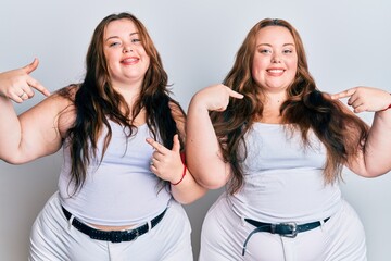 Plus size caucasian sisters woman wearing casual white clothes looking confident with smile on face, pointing oneself with fingers proud and happy.